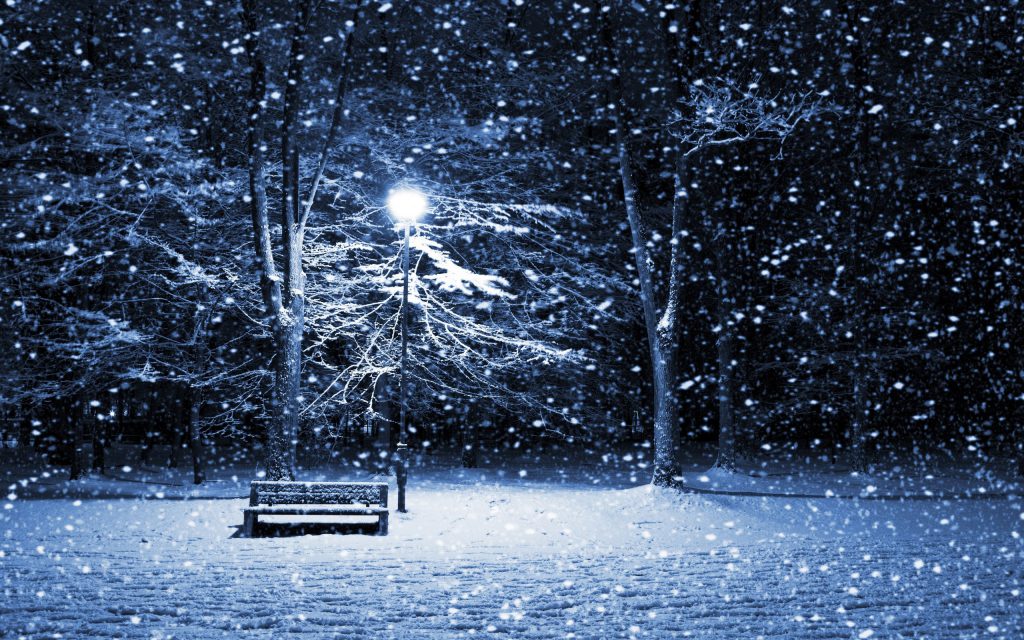 The Snowy Park Wallpaper - A snow covered park at night, with a light shining down on a snow covered park bench.